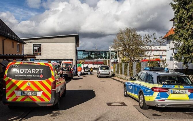 Einsatzkräfte der Rettungsdienste stehen vor einer Schule