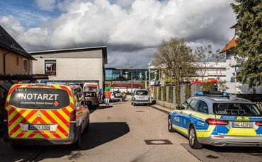 Einsatzkräfte der Rettungsdienste stehen vor einer Schule