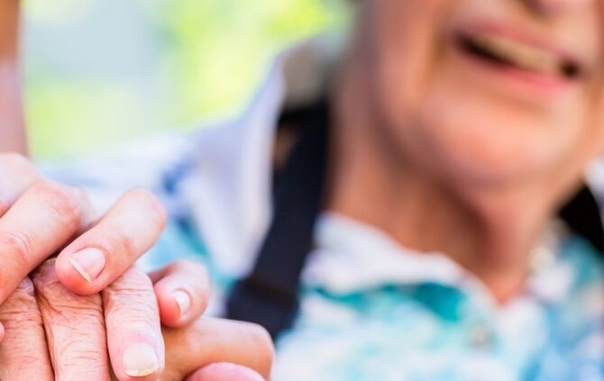 Nurse consoling senior woman holding her hand