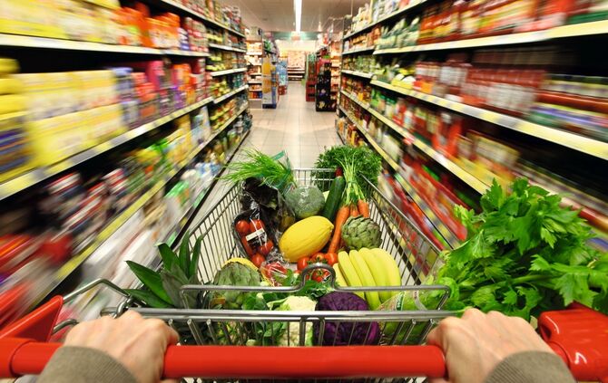 Lebensmittelabteilung, Voller Einkaufswagen wird durch einen Gang mit diversen Lebensmittel Produkten geschoben. Grosser Supermarkt, Selbstbedienung. Deutschland, Europa.Deutschland, Europa.