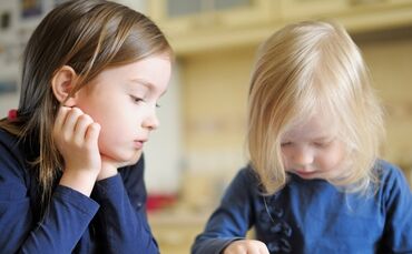 Two children playing with a digital tablet at home
