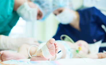 Neonatal Resuscitation. Doctor's team doing intensive therapy to newborn baby