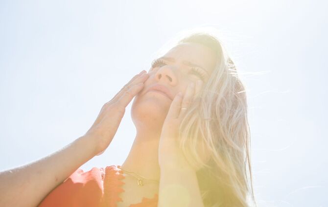 Eine Frau cremt sich mit Sonnencreme das Gesicht ein.