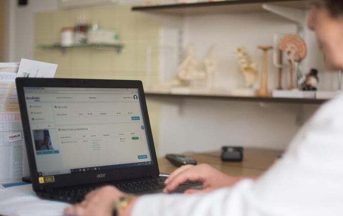 Eine Ärztin sitzt vor ihrem Laptop