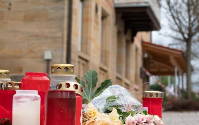 Blumen und Kerzen liegen vor dem Tatort in Rot am See