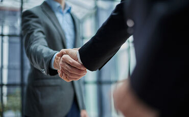 Two diverse professional business men executive leaders shaking hands at office meeting