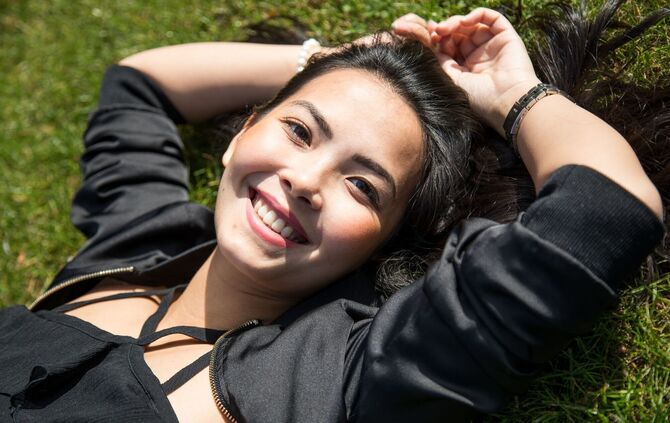 Eine Frau liegt lächelnd im Gras