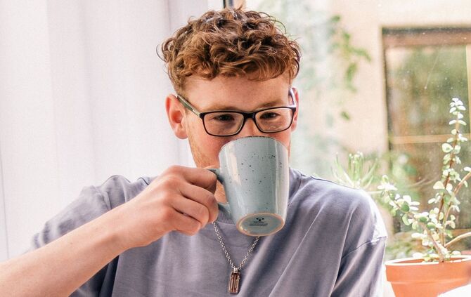 Ein junger Mann trinkt einen Kaffee.