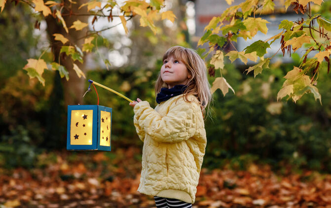 Little preschool kid girl holding selfmade traditional lanterns with candle for St. Martin procession. child happy about childre
