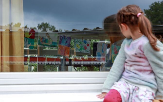 Ein Kind sitzt auf einer Fensterbank.