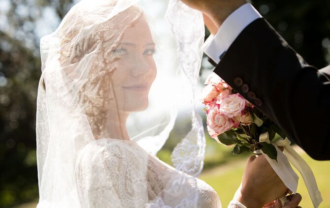 Ein Mann lueftet den Schleier seiner Braut