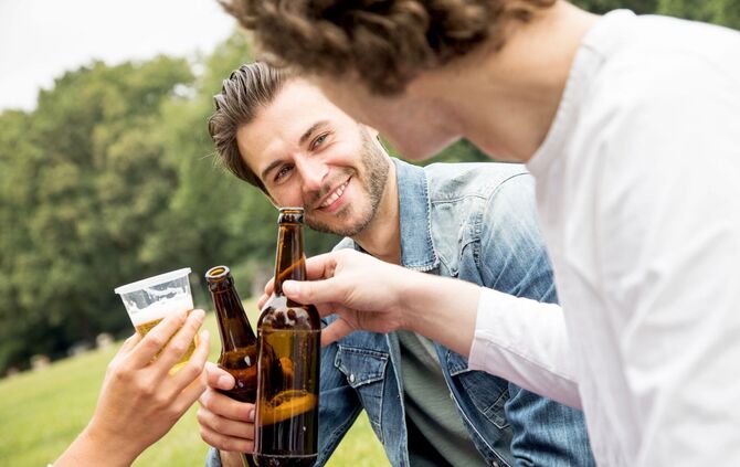 Zwei Männer stoßen mit Bier an.