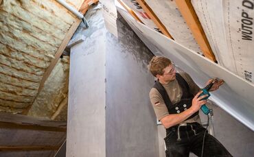 Ein Dachdecker bringt Isolierplatten auf