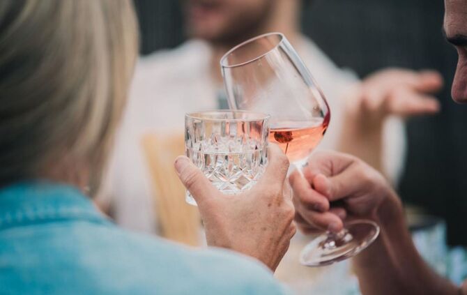 Zwei Menschen stoßen mit Wein und Wasser an