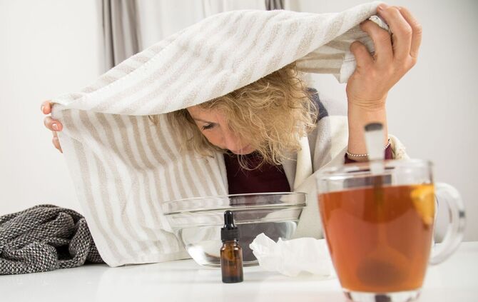 Eine Frau mit Handtuch über dem Kopf inhaliert