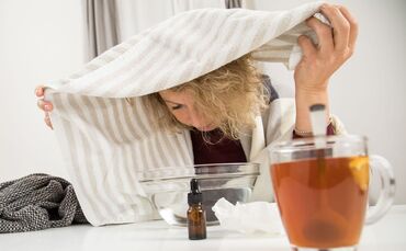 Eine Frau mit Handtuch über dem Kopf inhaliert