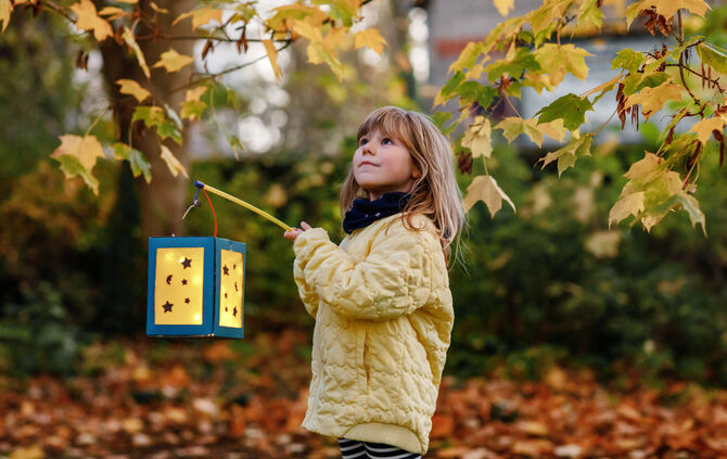 Little preschool kid girl holding selfmade traditional lanterns with candle for St. Martin procession. child happy about childre
