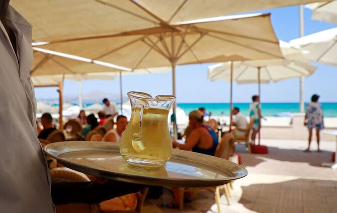 Ein Kellner serviert an einem mallorquinischen Strand einen Wein