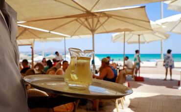 Ein Kellner serviert an einem mallorquinischen Strand einen Wein