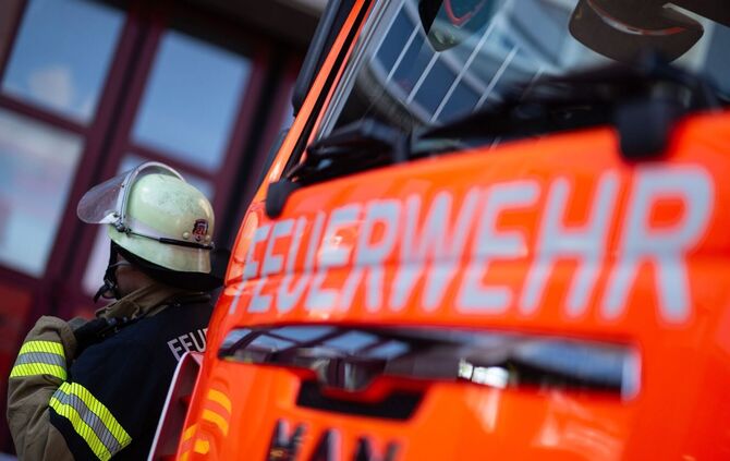 Feuerwehrmann steht neben einem Feuerwehrauto