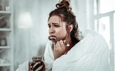 Woman eating chocolate pasta because of being stressed
