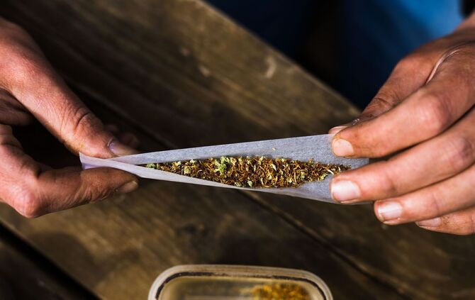 Ein Mann dreht sich mit Cannabis und Tabak einen Joint
