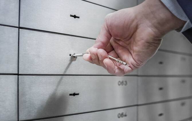 Human hand opening safe deposit box