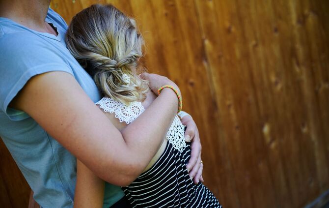 Ein Mädchen wird von seiner Mutter in den Arm genommen