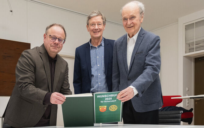 Oberbürgermeister Bernd Hornikel, Friedrich Munsberg und Waldemar Junt (von links) blicken gemeinsam ins Wunschbuch 2025.