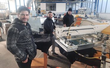 Andreas Kamm mit seinen Angestellten Erhan Demirdas und Fernando Rizzo (von links) an der Textildruckmaschine.