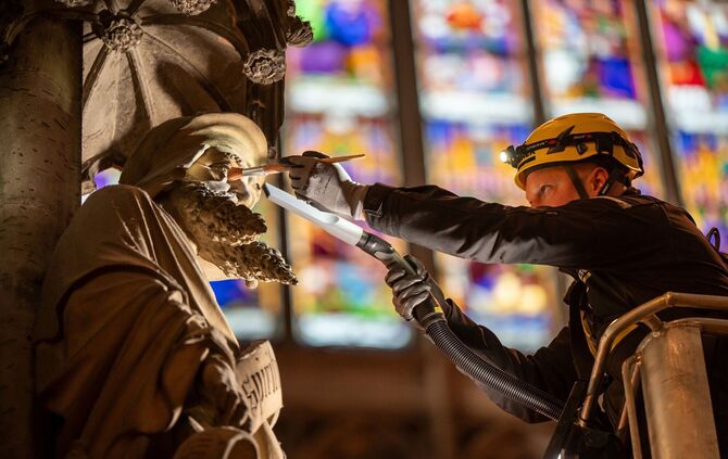 Ein Kärcher-Mitarbeiter entfernt Staub und Kerzenruß von einer Figur im Kölner Dom - in bis zu 43 Metern Höhe.
