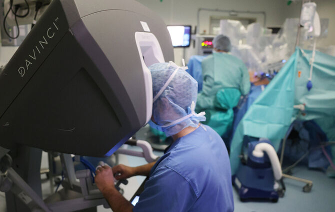 Vorne blickt Dr. Istvan Degrell nach links aufs dreidimensionale DaVinci-Kamerabild aus dem Inneren der Patientin - die Frau, di