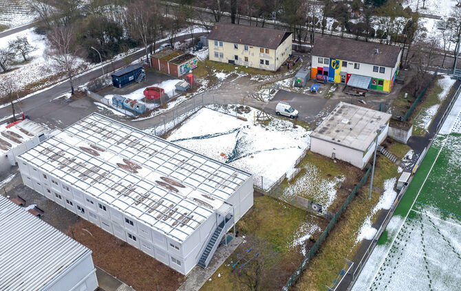 Eine aktuelle Luftbildaufnahme des Jugendzentrums (rechts hinten, bunte Fassade) mit angrenzender Flüchtlingsunterkünften von Ge