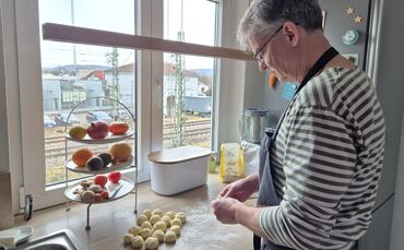 Den Hefeteig hat Markus Wagner schon vorbereitet. Jetzt werden die kleinen Teigkugeln auseinander gedrückt, damit der Teig flach