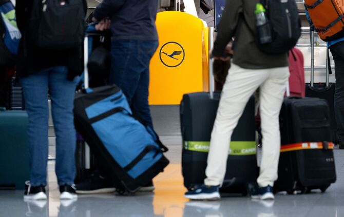 Passagiere warten an einem Check-In-Schalter der Lufthansa