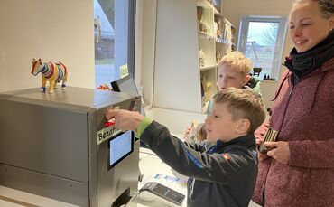 Stammkundin Christiane Merz mit Jakob (11) und Josia (9, vorn) Lechner, die demonstrieren wie der Münzwechselautomat funktionier