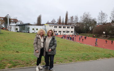 Rektorin Ulrike Dengler (links) und Konrektorin Alicia Grötsch - hinter ihnen sind die Hungerbergschule zu sehen, der Wiesenhang