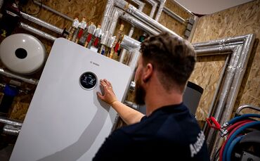 Handwerker zeigt an einer Wärmepumpe auf die Anzeige