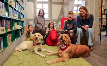 Die Lesehunde Feli und Abby mit ihren Besitzerinnen und kleinen Büchereibesuchern in Stetten.