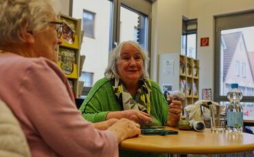 Wertvolle ehrenamtliche Hilfe: Monika Peters (rechts) erklärt Gisela Luckert, wie ihr Handy-Wecker funktioniert.