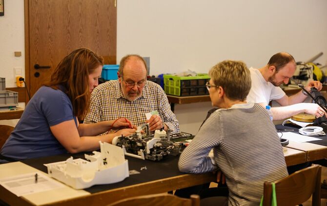 Konzentriert wird an einem kaputten Gerät gearbeitet.