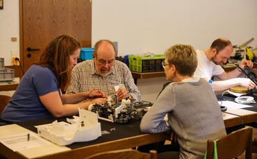 Konzentriert wird an einem kaputten Gerät gearbeitet.