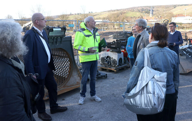 Dirk Siegel, Geschäftsführer Bildungszentrums Bau (Bildmitte in gelber Jacke) erklärt Besuchern die Neubau-Pläne in Remshalden.