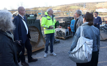 Dirk Siegel, Geschäftsführer Bildungszentrums Bau (Bildmitte in gelber Jacke) erklärt Besuchern die Neubau-Pläne in Remshalden.
