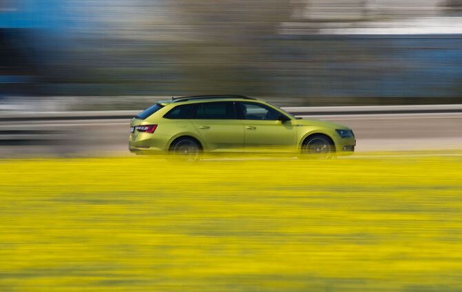 Auto fährt an einem Rapsfeld entlang