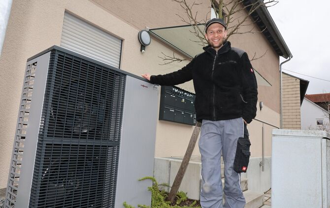Nico Eifer mit Außengerät der von ihm eingebauten Wärmepumpe an einem Mehrfamilienhaus in Schorndorf.