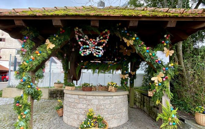 Der Osterbrunnen in Buoch ist festlich mit Girlanden, bunten Ostereiern und Blüten geschmückt.