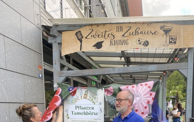 Claudia Fischer und Dirk Jerusalem am Tauschregal vor dem dasWohnzimmer.