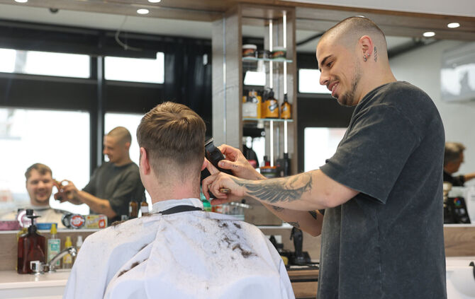 Mitarbeiter Nikola Marjanović (rechts) bei der Rasur von Daniel Chieffo.