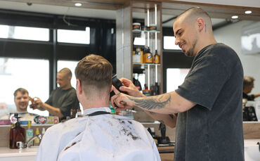 Mitarbeiter Nikola Marjanović (rechts) bei der Rasur von Daniel Chieffo.